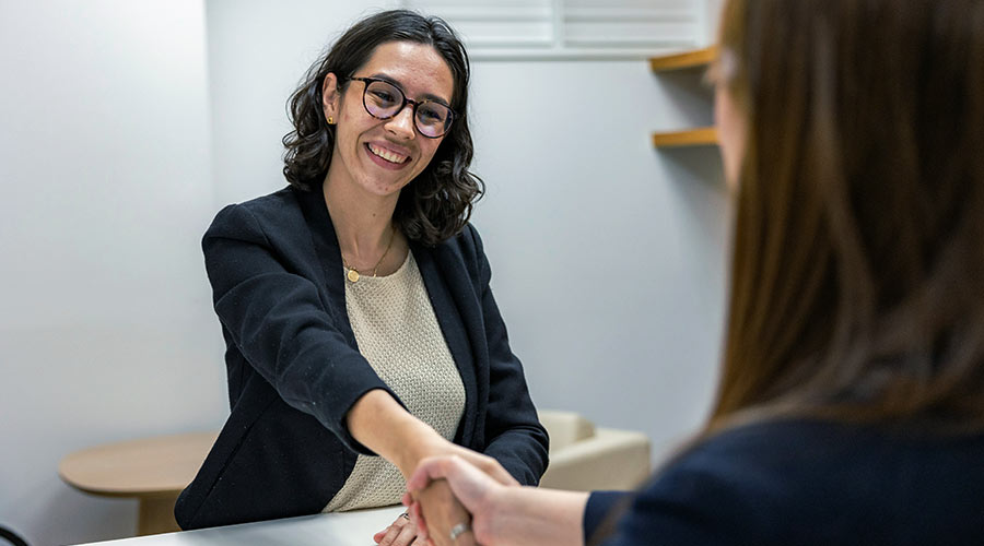Une jeune femme serre la main d'une autre avec le sourire lors d'un entretien